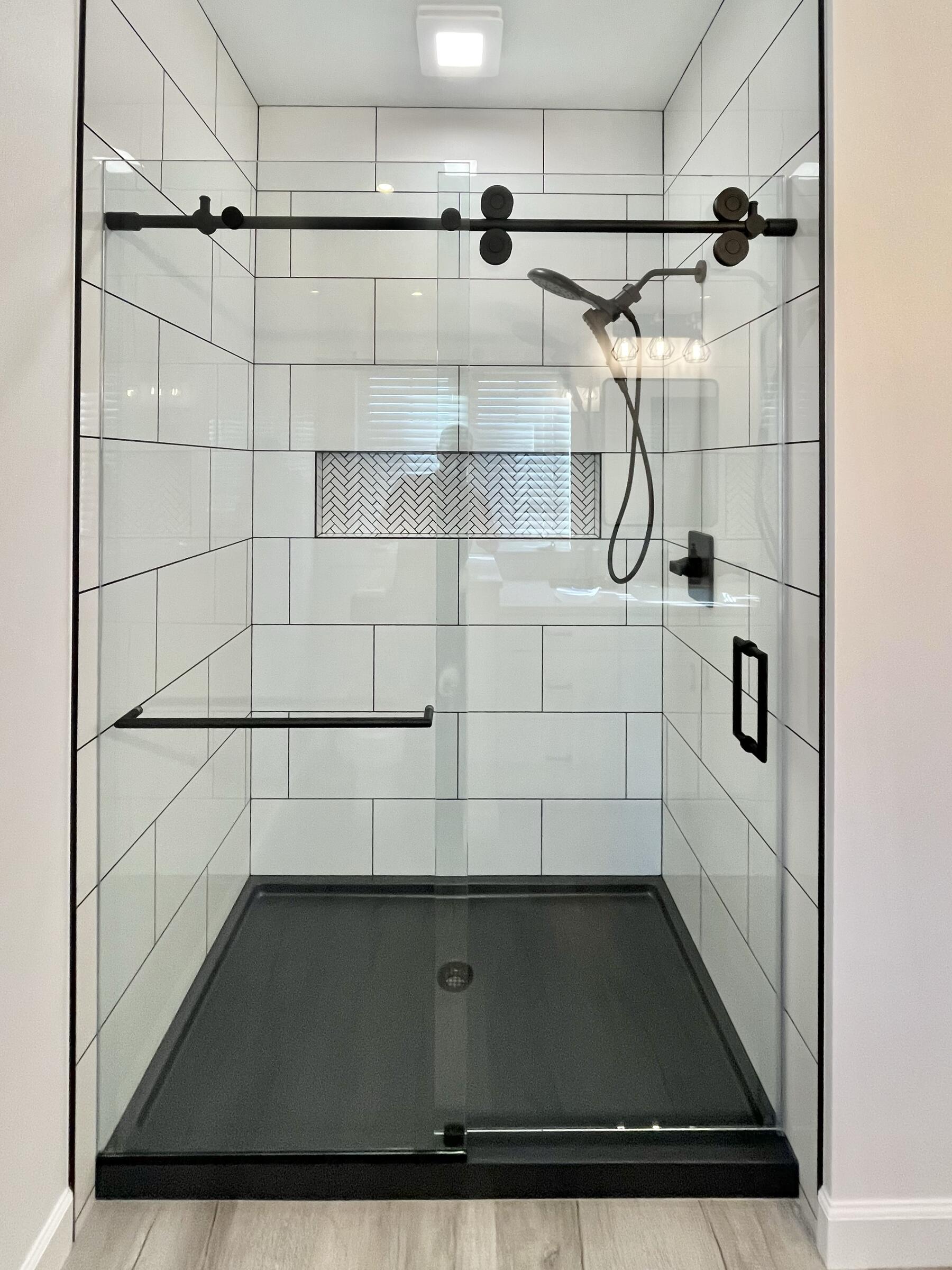 Frameless bypass sliding shower door with a black header bar