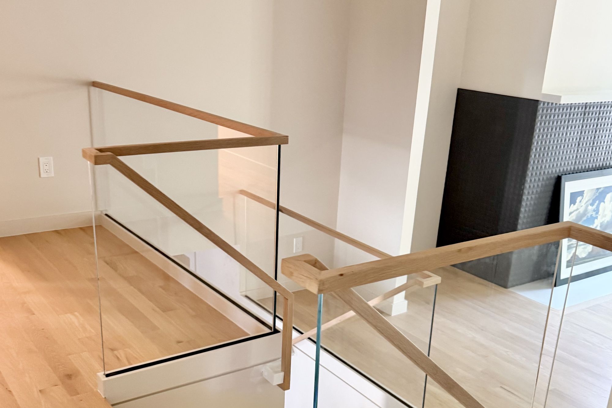 Frameless glass stair railing with a wood top cap