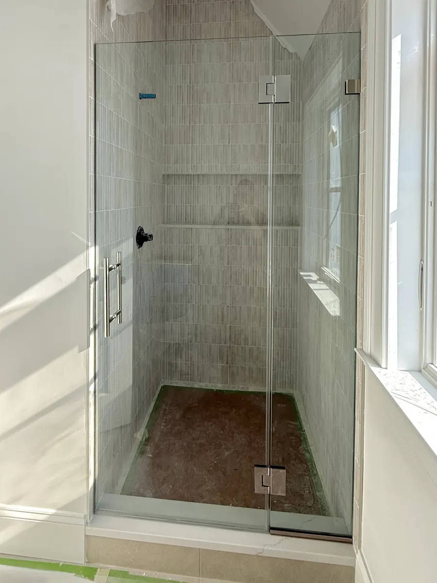 Door and panel frameless glass shower enclosure, polished chrome hardware