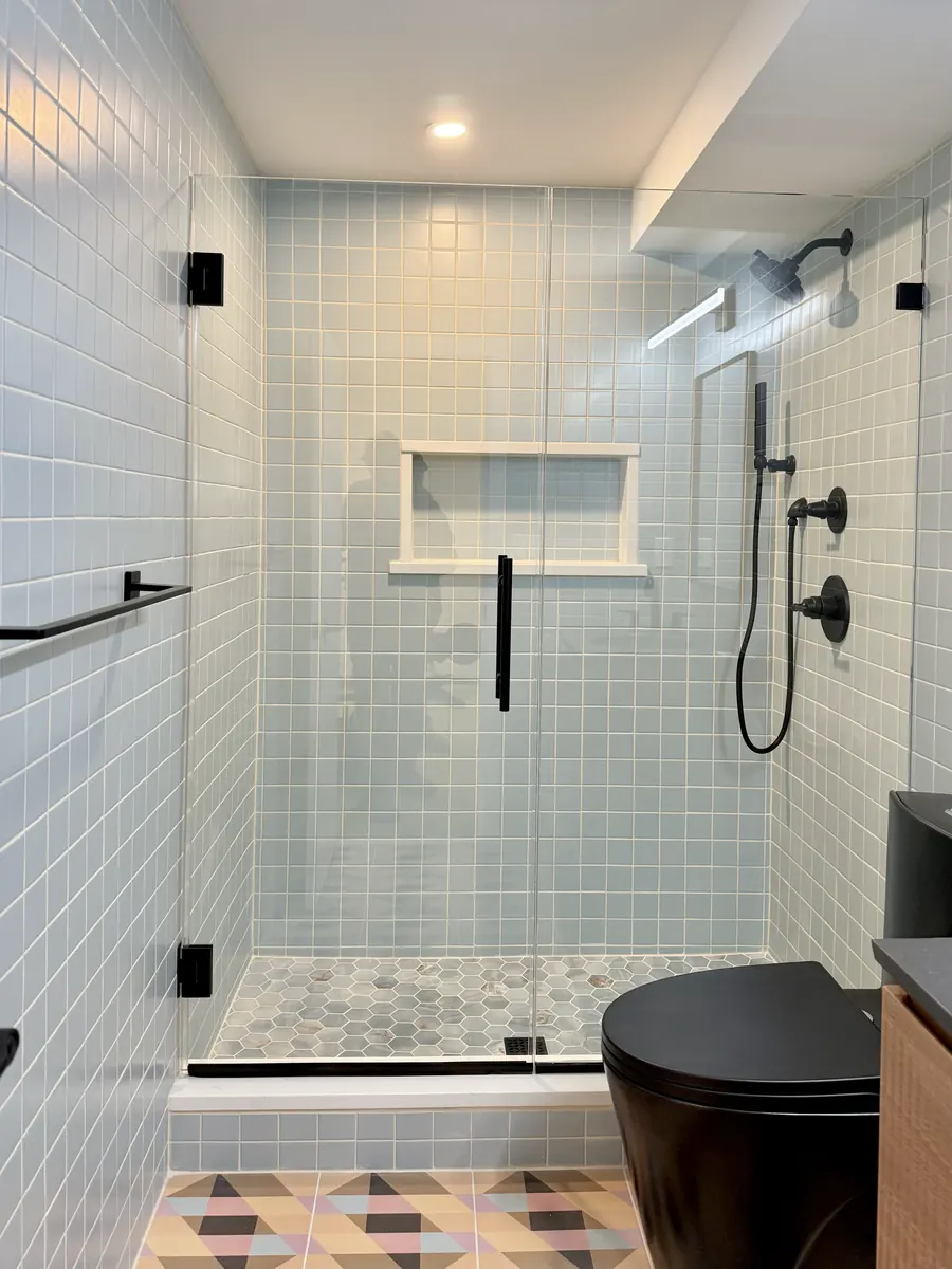 Door and panel frameless glass shower enclosure, matte black hardware, retro tile