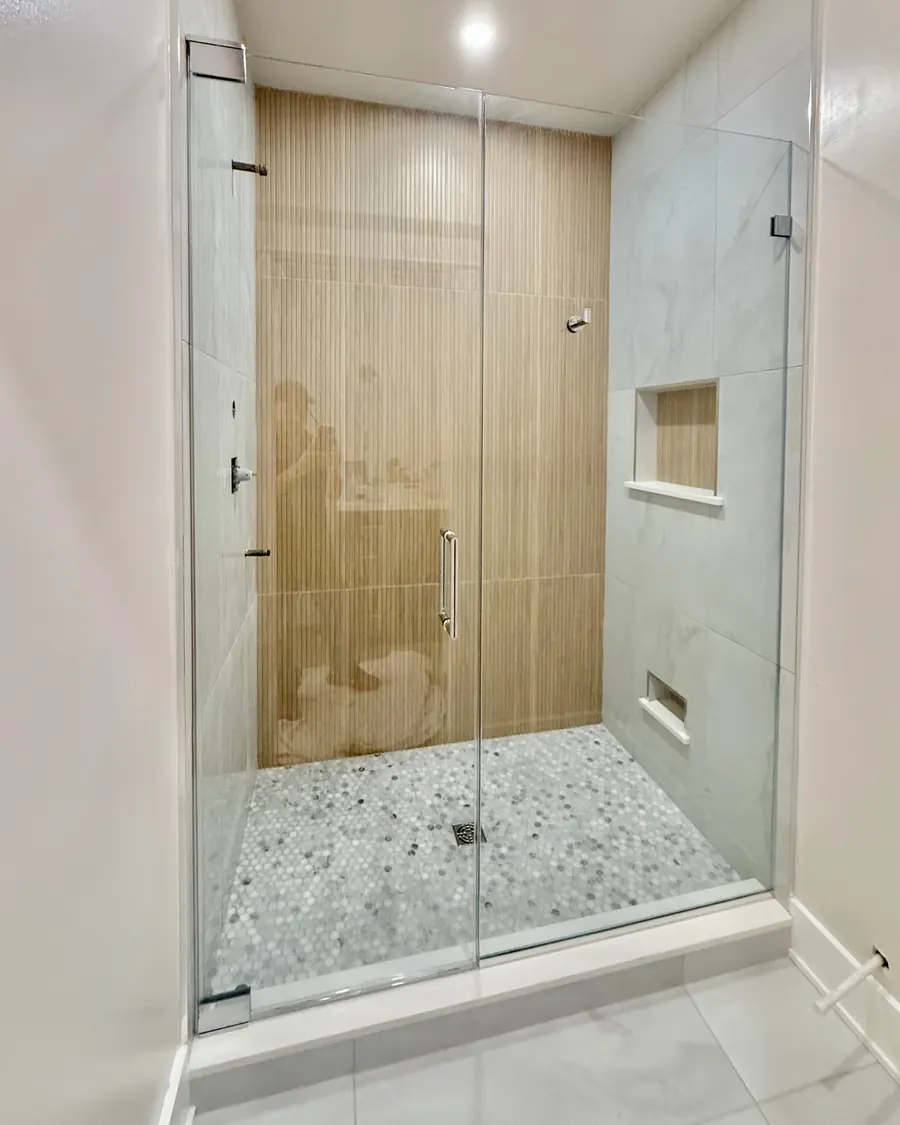 Door and panel frameless glass shower enclosure, polished chrome hardware, wood tile