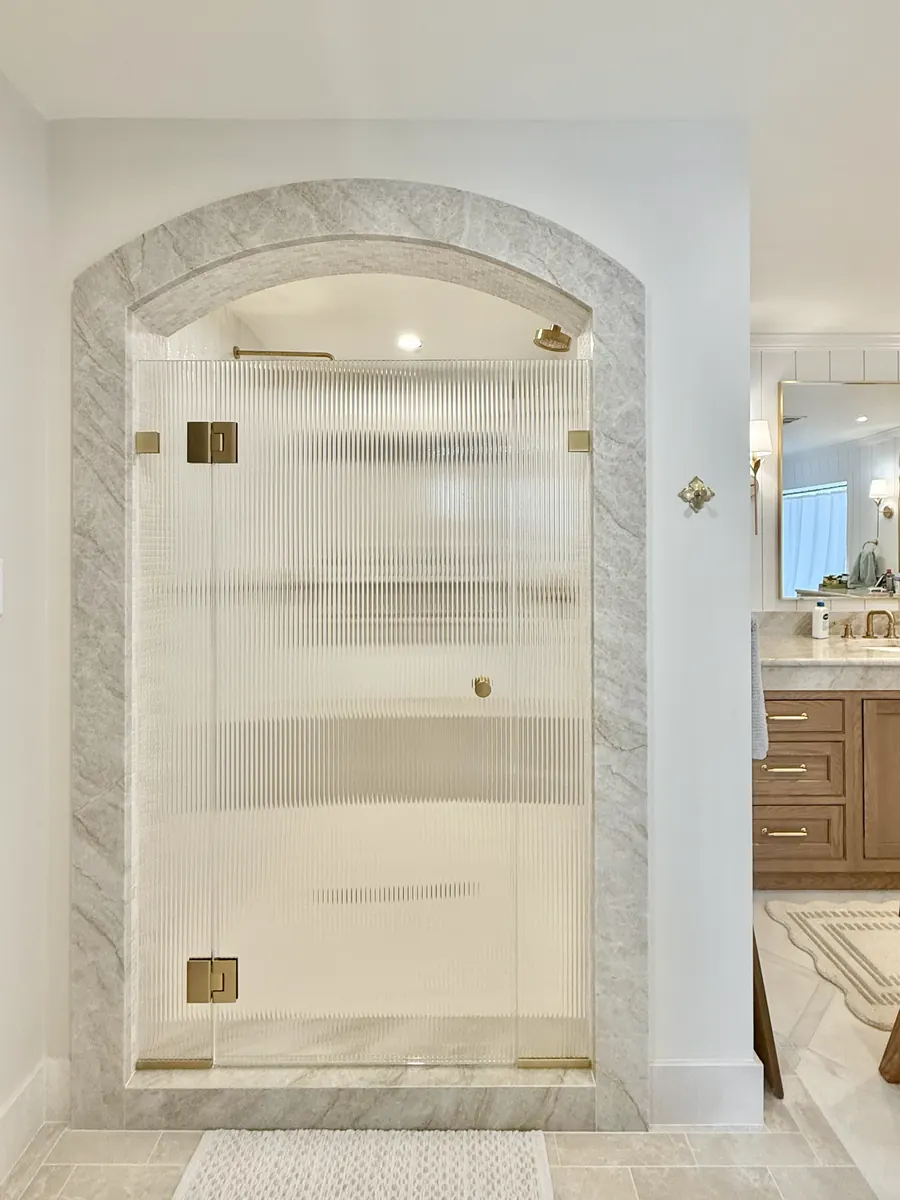 In-line panel frameless glass shower enclosure, satin brass hardware, reeded glass