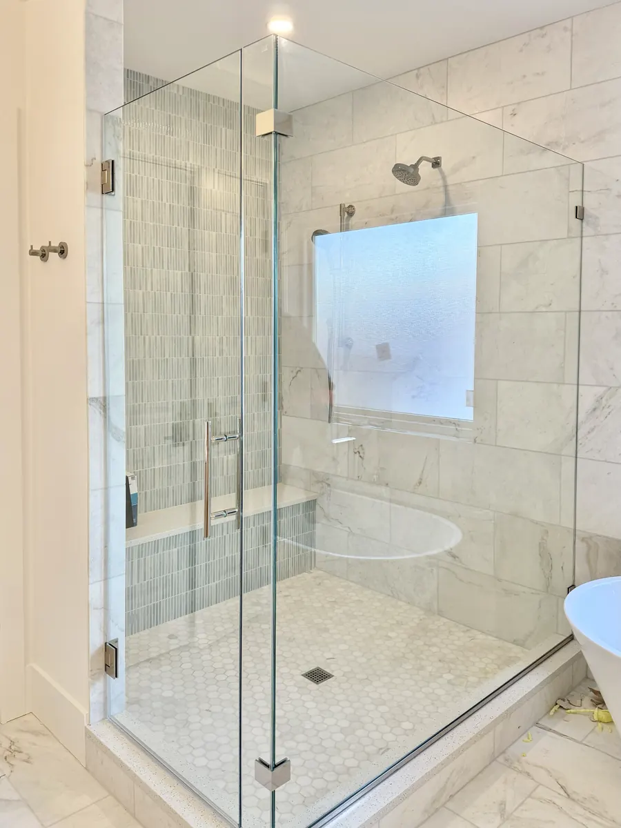 Frameless sliding shower door, with a 90 degree return panel, polished chrome hardware, ladder pull