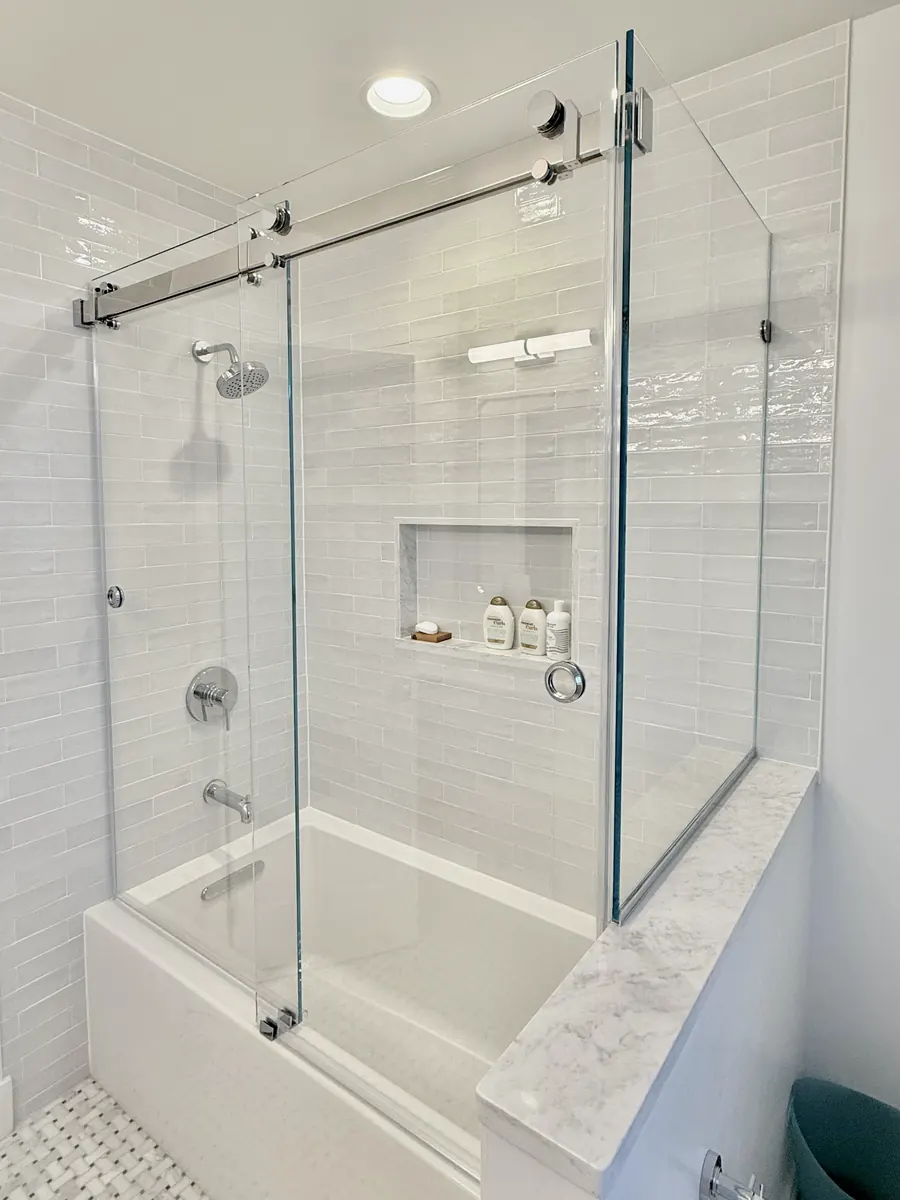 Titan Duo series frameless sliding shower door, over a tub, with a 90 degree return panel, polished chrome hardware